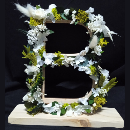 Letra de madera en flores preservadas